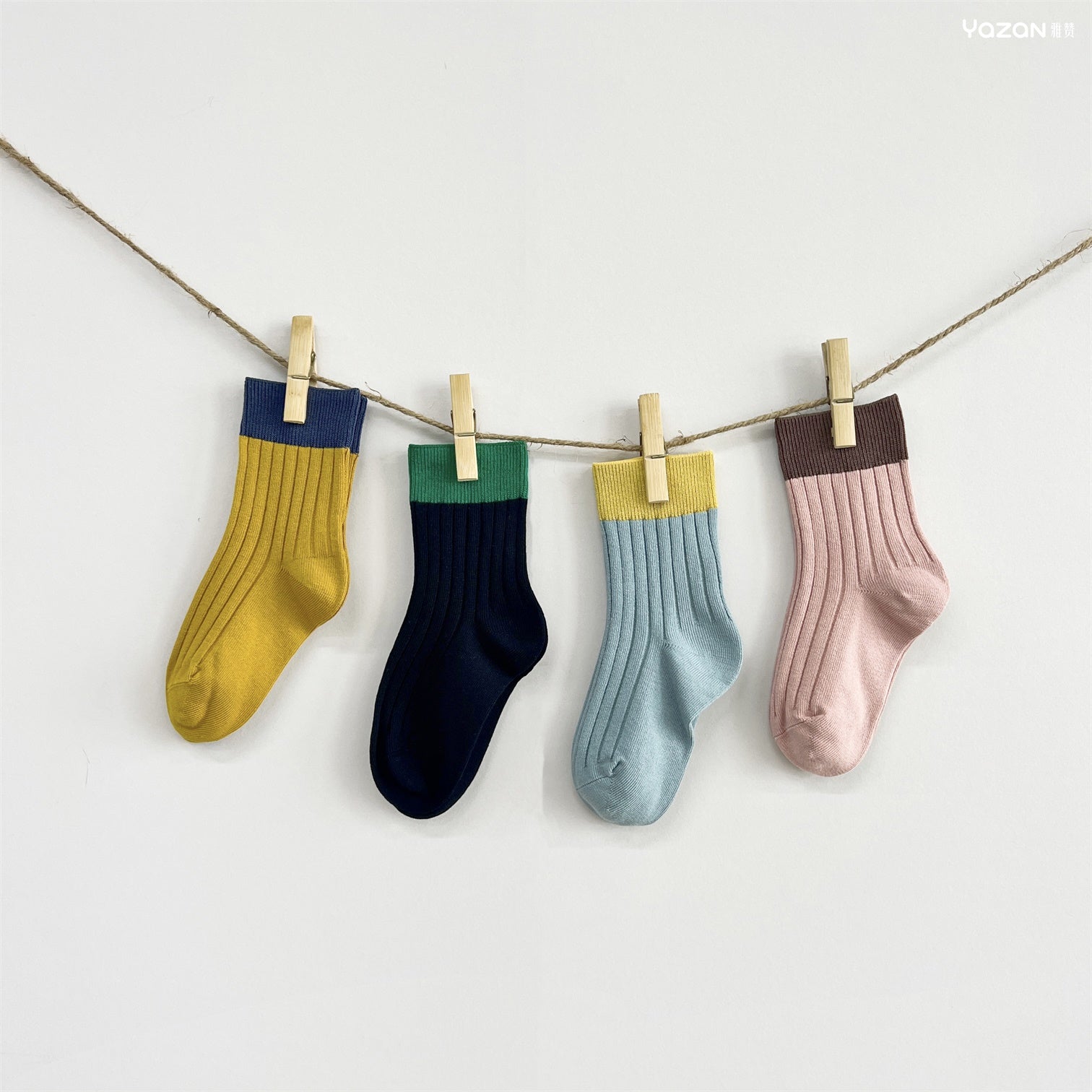Four colorful socks hanging on a line with clothespins against a white background
