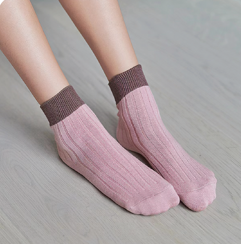 Pink socks with brown tops worn by a person on a light wooden floor.