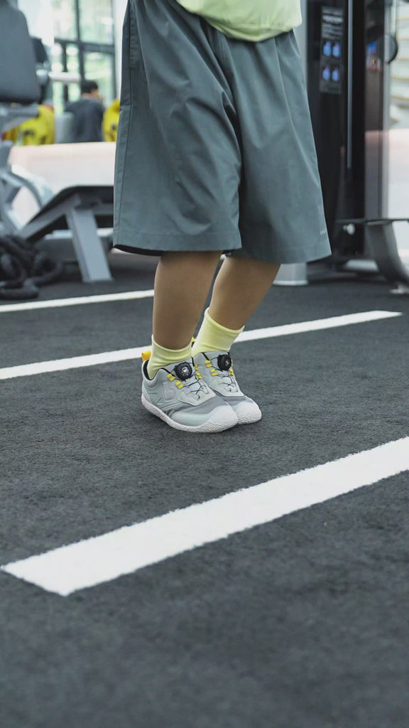 A kid is wearing and testing a pair of Barefoot Kids Trainers by Little Blue Lamb